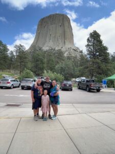 Dave Engel and his family smiling in front of Devils Tower National Monument in Wyoming